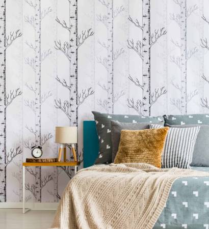Beige blanket on king-size bed in simple bedroom with lamp and clock on nightstand
